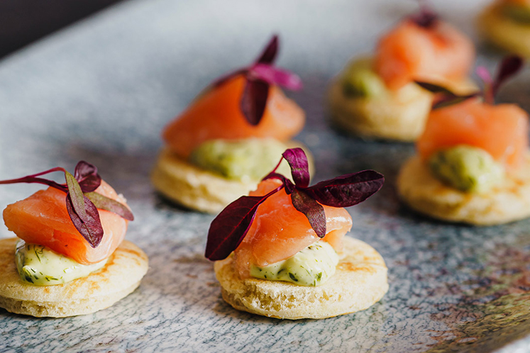 Gerookte zalm geserveerd op een blini met basilicummayonaise